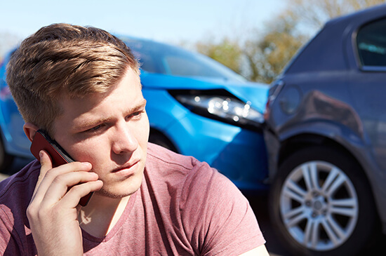 young man looking concerned on mobile after car accident