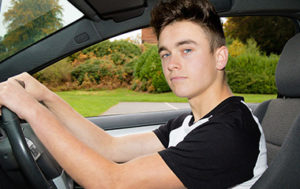 confident young male driver in car behind the wheel