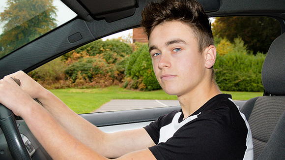 confident young male driver in car behind steering wheel