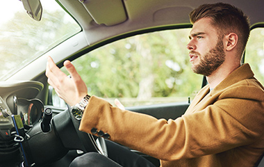 young man driving getting frustrated with another driver