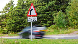 car speeding past 20mph maximum speed sign on English country road