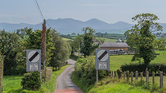 national speed limit signs rural lane with mountains in the distance